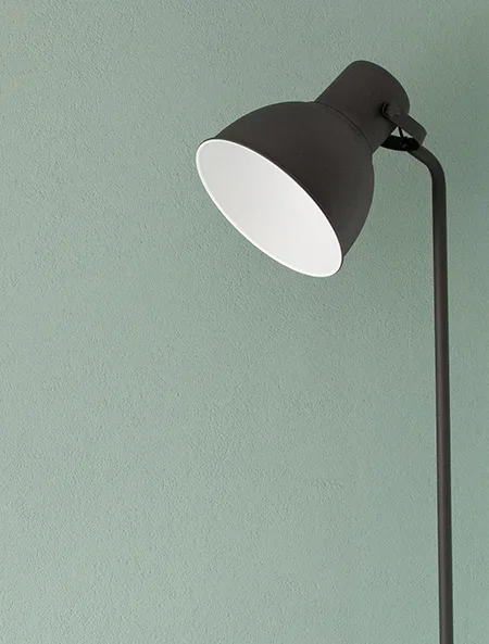 A black desk lamp against a light green wall